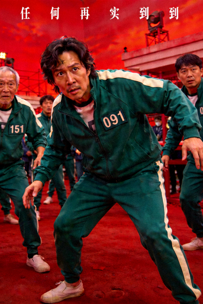 《鱿鱼游戏》剧照，参与者身穿绿色运动服在红色场景中